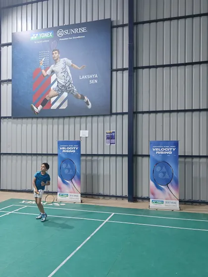 A player takes a shot on the court during our special event with Yonex. The atmosphere is always energetic and motivational, surrounded by banners of badminton champions.