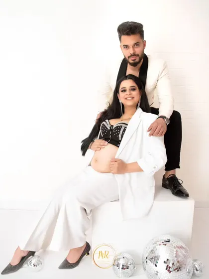 A classic seated portrait from the modern black-and-white maternity session, capturing a moment of quiet connection between the couple.
