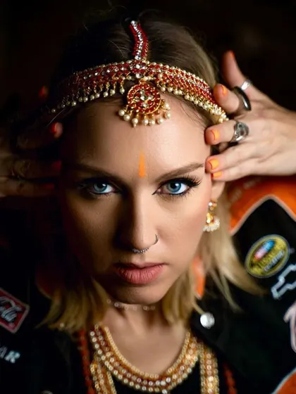 A fierce and captivating look for Uma Shanti. The sharp, neon orange liner and traditional Indian jewelry create a powerful fusion of modern and classic styles.