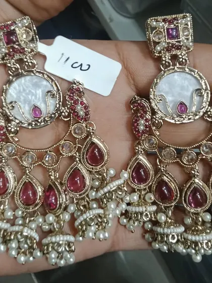 Exquisite chandbali earrings with a mother-of-pearl centrepiece, surrounded by ruby-coloured stones and finished with pearl and gold bead drops. The craftsmanship on these is exceptional.
