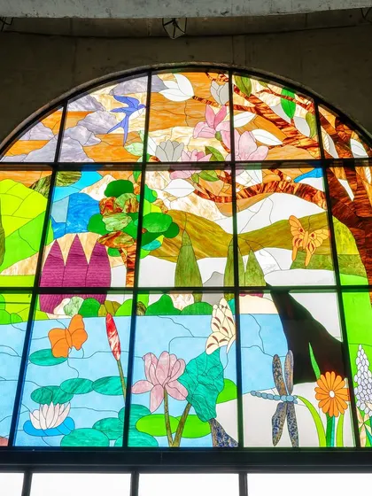 A detailed view of the intricate stained glass mural at Mount Carmel. The artwork depicts scenes from nature, blending symbolism with vibrant colour to enrich the architectural experience for students and visitors.