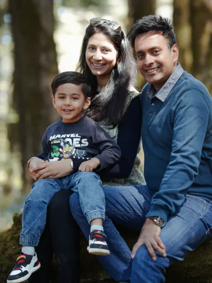 A beautiful, classic family portrait taken in the woods, showcasing their happy smiles and the natural beauty of Shimla.
