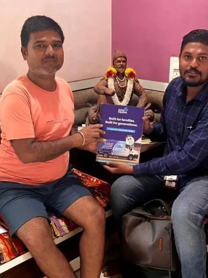 A customer holding our "Built for Generations" booklet in front of a Shivaji Maharaj statue.