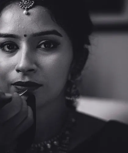 A dramatic black and white close-up of the bride's makeup being applied. This shot focuses on the details and artistry of the getting-ready process.