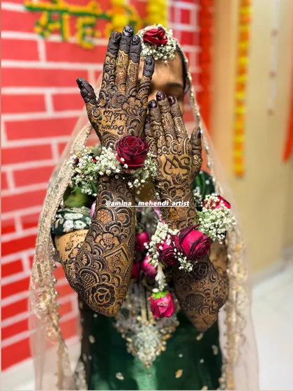 A full bridal look, with the bride's face partially hidden, drawing all attention to the intricate mehendi and floral bracelets.