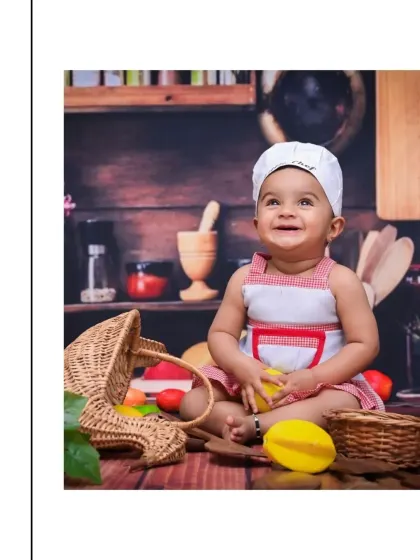 A joyful shot from a 'Little Chef' setup. Dressed in a chef's hat and apron, this baby is surrounded by kitchen-themed props, creating a fun and imaginative scene.