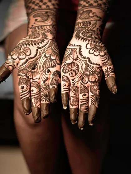 A detailed close-up of a bride's hands, showcasing the beautiful and intricate patterns of her wedding mehndi. This shot celebrates the traditional artistry of the henna.
