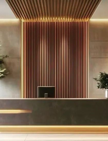 A striking reception area with a minimalist dark stone desk, accented by warm lighting from below. The back wall features dramatic copper-toned fluted panels, creating a luxurious and memorable first impression.