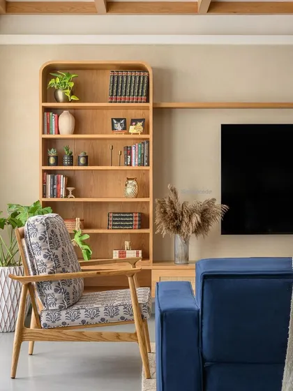 A close-up of the TV area in 'Cover me in Sunshine', showing the curved bookshelf and contemporary blue sofa. The design is a perfect example of our modern cottage aesthetic.
