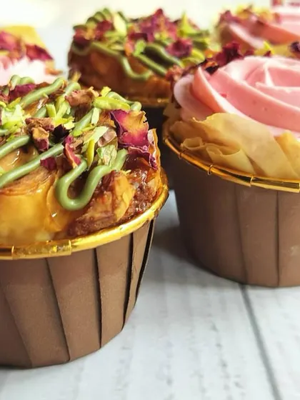 A close-up of the Eid special Baklava Cupcakes, showcasing the contrast between the pistachio-drizzled ones and the rose-piped ones.