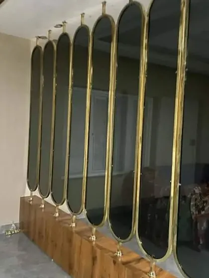 A simple yet effective partition made from a series of rotating oval glass panels in a gold frame. This allows for adjustable levels of privacy and light.