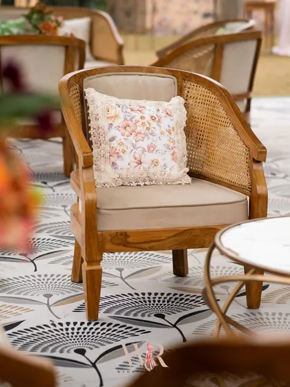 A close-up of the seating, showing the mix of textures from the cane chair, the printed floor, and the custom floral cushion. These details are key to creating a rich, layered boho look.