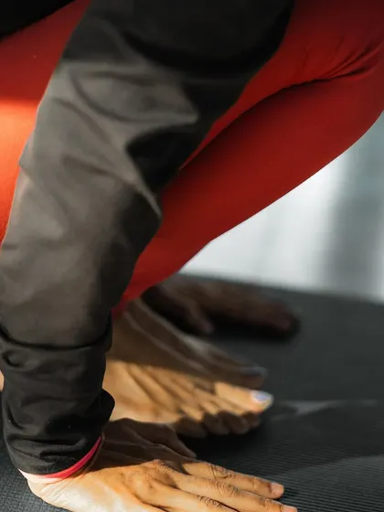 A close-up shot of hands and feet in a deep squat, illustrating the focus and grounding required in asana practice. Every session is a chance to build a better mood.