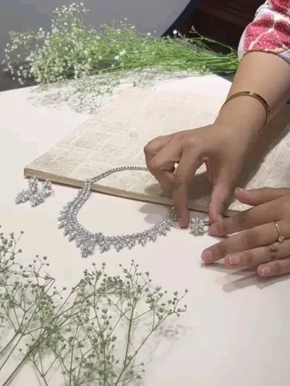 A stylist's hands carefully arranging the necklace and props for the Nanagram Jewels flatlay.