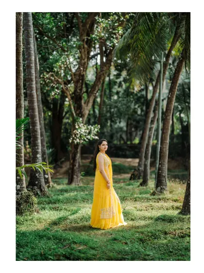 A stunning outdoor portrait of the bride in her yellow Haldi dress, surrounded by lush greenery.
