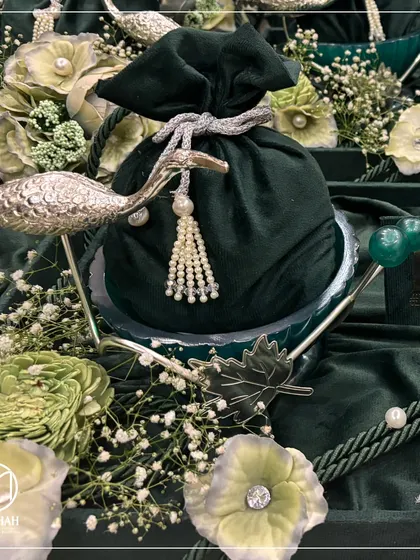 A detailed shot of the Heron Bowl, focusing on the silver-finished bird, the pearl-tasseled velvet potli, and the green agate stone accents. Every detail is crafted with care.
