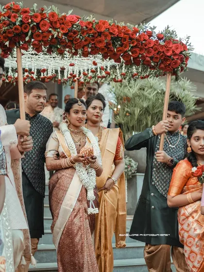 A beautiful perspective of the bride's entrance, walking down the stairs under a canopy of red roses. It's a moment of pure elegance and anticipation.