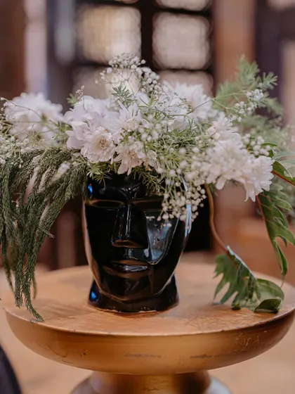 This unique black face-shaped vase filled with baby's breath and white florals was a conversation starter and added an artistic touch to the Sangeet decor.