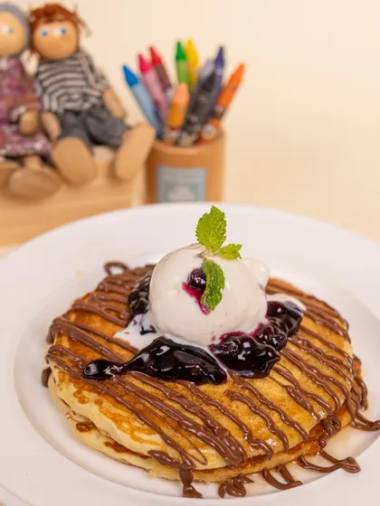 Our fluffy pancakes topped with ice cream, blueberry compote, and chocolate drizzle are a breakfast dream come true.