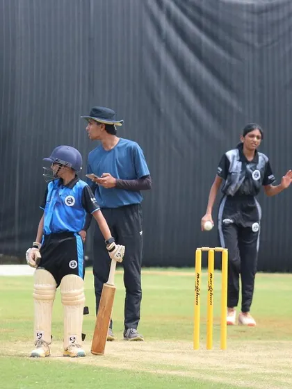 A practice session under the watchful eye of an umpire, ensuring players learn the rules and etiquette of the game.