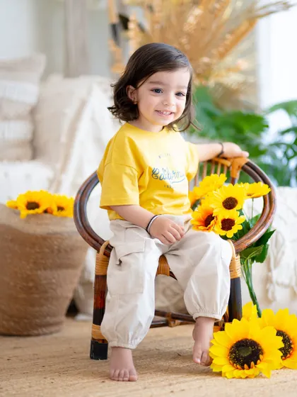 A bright and sunny portrait with sunflowers. This little one's happy smile is as bright as the flowers beside her.