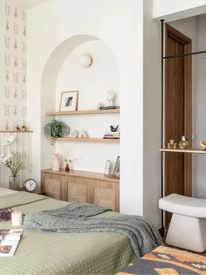 Another view of the cozy bedroom, showing the arched niche, wall lights, and the sleek floor-to-ceiling mirror.