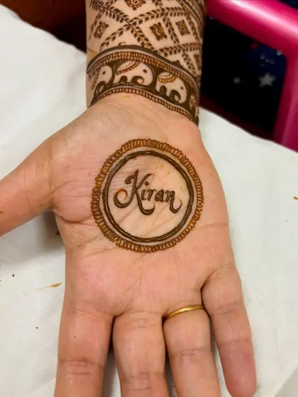 The name "Kiran" shown with the fresh henna paste, before the full design was completed.