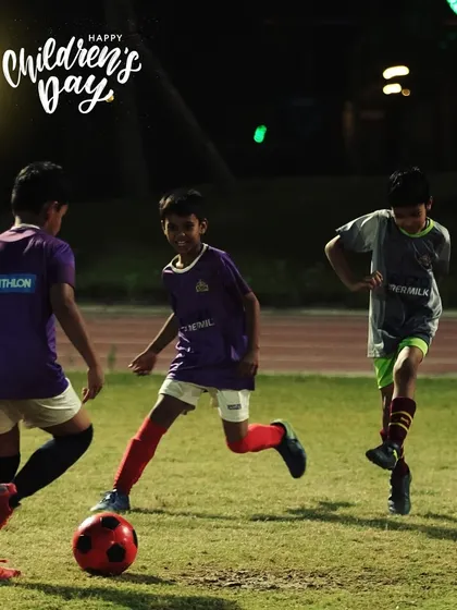 Three of our youngest players enjoying a game under the lights. This is what grassroots football is all about: fun, friends, and a football.