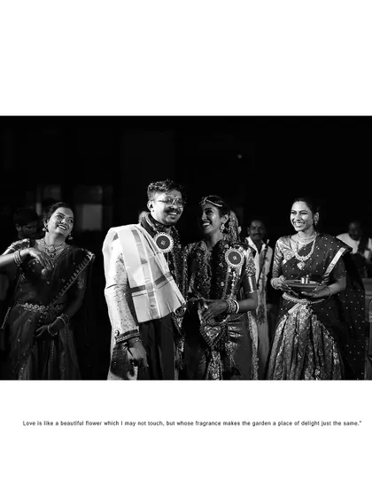 A candid black and white photo of the couple and their family laughing together during the wedding rituals.