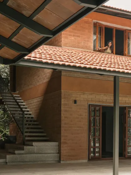 The multi-level design of Villa Maati creates interesting visual connections. Here, a view from the ground floor looks up towards an open window and the exterior staircase, highlighting the home's dynamic structure.