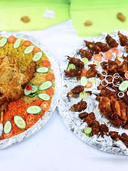 Two of our popular platters side-by-side. One with colourful biryani and roasted chicken, and the other with an assortment of fried chicken and quail.