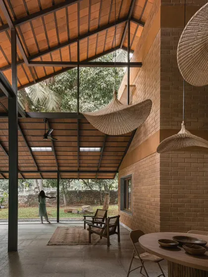 The double-height living space at Villa Maati showcases our use of volume and texture. The exposed brick walls and tiled roof are complemented by large woven pendant lights, creating a warm and inviting atmosphere that feels both grand and intimate.