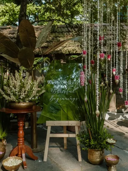 A welcome sign on a mirrored easel, reflecting the lush greenery of the venue.