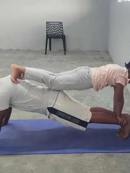 This wall-assisted double plank shows a different foot placement, demonstrating how we modify poses for safety and effectiveness.