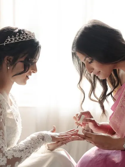 A bridesmaid helps the bride with her nails, a small, intimate moment of friendship and support.