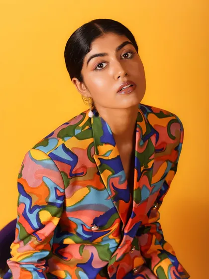 A classic beauty shot with a direct, engaging gaze. The vibrant colors of the jacket frame her face perfectly.