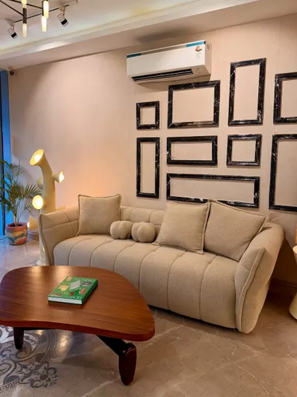 A full view of our flange-trim bouclé sofa, paired with an organic-form coffee table and sculptural lamp. This setup highlights how we blend different textures and shapes to create a harmonious living space.