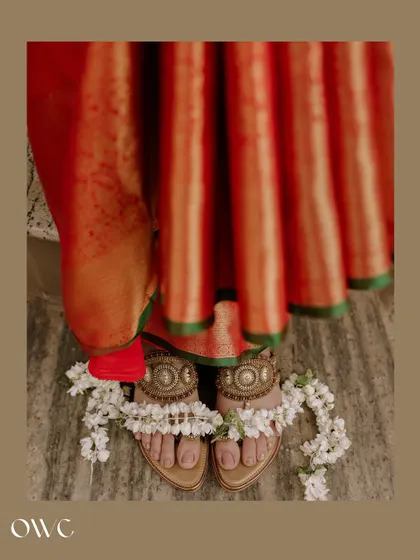 An artistic detail shot of the bride's feet, adorned with beautiful sandals and flowers.