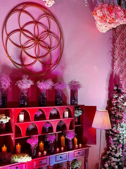 A beautifully styled console table at the 'Anant' wedding, featuring the Flower of Life symbol, abundant florals, and soft candlelight to create a welcoming and elegant atmosphere.