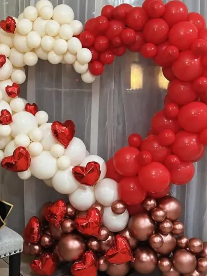 I love getting creative with balloons. This heart-shaped balloon arrangement uses a mix of red, white, and metallic rose gold balloons to create a beautiful and eye-catching photo backdrop for any romantic occasion.