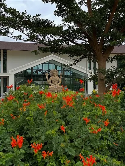 Summer blooms frame the entrance to our main building, where the statue of Lord Dhanvantari resides. Nature is in full celebration here, welcoming you to rejuvenate.