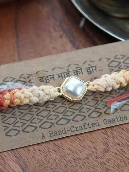 A close-up of the Kundan Rakhi on its packaging. The message reads 'Behen Bhai ki Dor' (the thread of a sister and brother).