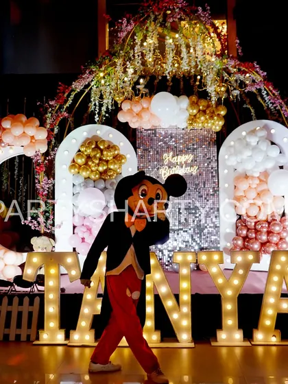A Mickey Mouse mascot poses in front of a teddy bear themed stage, showing how we can add character entertainment to any party.