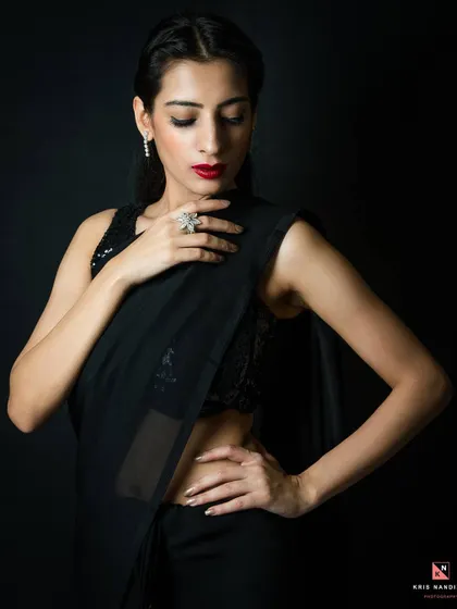 A full-body shot of the 'Blackburn' series, showing the model's pose and the elegant drape of the black saree. The low-key lighting adds a touch of drama and sophistication.