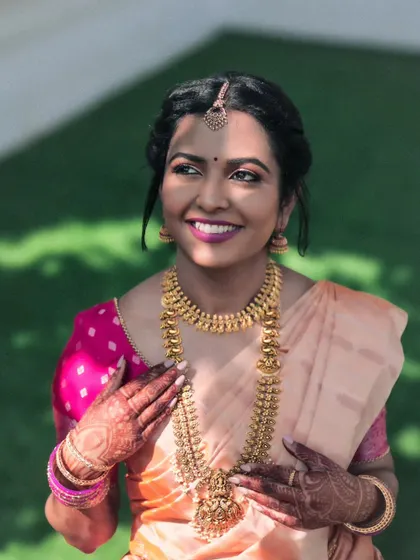 Bathed in sunlight, the bride looks radiant and happy. This portrait captures her beautiful smile, the intricate gold jewelry, and the delicate henna on her hands, all glowing in the natural light.