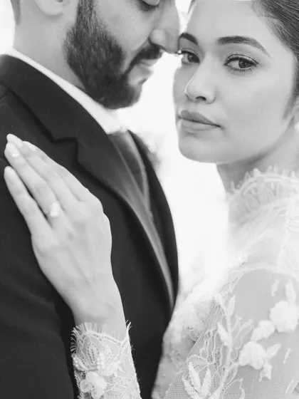 A delicate and intimate black and white portrait. The focus on the bride's hand on the groom's chest and her soft expression creates a timeless and romantic feel.