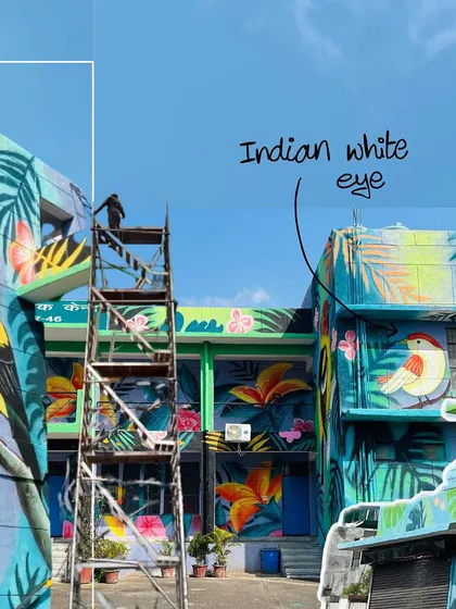 A shot showing me on the scaffolding during the project, with a callout identifying the 'Indian white-eye' bird. The mural serves an educational purpose by showcasing local wildlife.