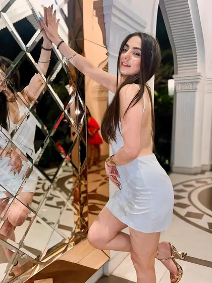 Posing against a diamond-patterned mirror wall in my white dress. I love finding cool spots for photos that make the outfit pop.