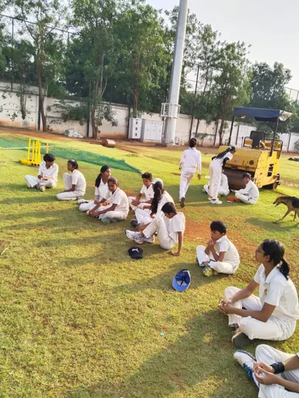 Young female cricketers resting between drills, sharing a moment of camaraderie at the Chinchwad ground.