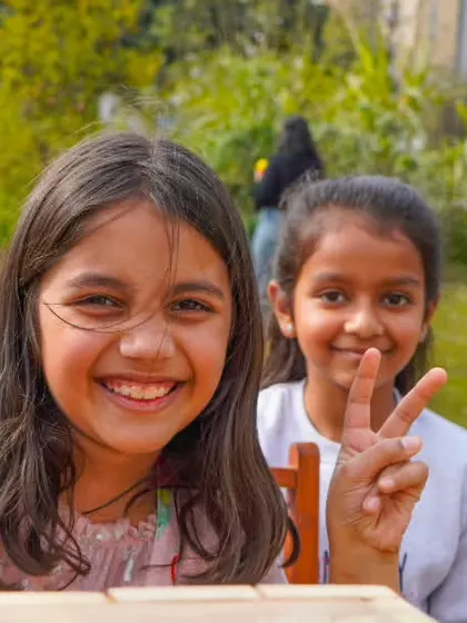 Two happy girls giving peace signs, celebrating their fun day at the farm.